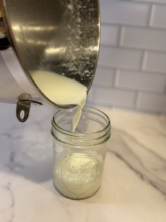 Pouring fresh buttermilk into a jar after making homemade butter