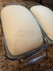 Homemade bread dough risen in a loaf pan, ready to bake