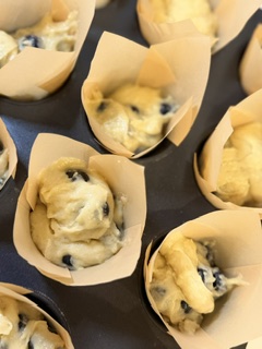 Homemade blueberry muffin batter filled into cupcake liners in a muffin pan, ready to bake.