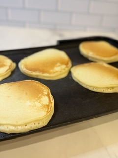 Homemade buttermilk pancakes cooking on a hot griddle