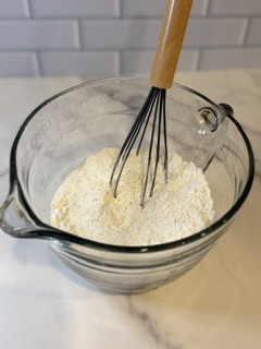 Dry ingredients for homemade chocolate chip cookies in a glass mixing bowl.