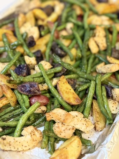 Cooked chicken, roasted potatoes, and fresh roasted green beans on a sheet pan.