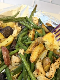 Chicken, Roasted potatoes, and green beans sheet pan dinner with a fork holding a bite of potato.