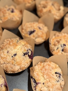 Freshly baked homemade blueberry muffins with golden brown crumble topping in a cupcake pan.