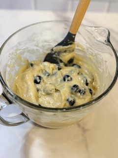 Homemade blueberry muffin batter with fresh blueberries mixed in, ready to be portioned into muffin cups and baked.