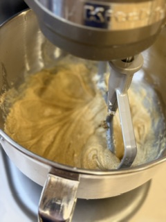Wet and dry ingredients for homemade chocolate chip cookies mixing together in a stand mixer.