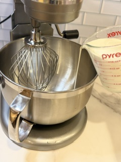 Pouring buttermilk into a mixing bowl while making homemade butter