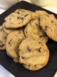 Freshly baked homemade chocolate chip cookies arranged on a black plate.