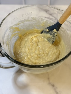 Homemade blueberry muffin batter in a mixing bowl before adding fresh blueberries, ready to be folded together for baking.
