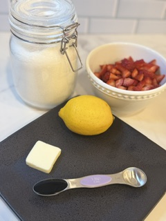 Fresh strawberries, sugar, and lemon juice arranged as ingredients for homemade strawberry jam